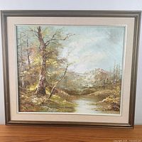 Frontal view of the framed oil painting showing a mountain landscape with river and forest, exhibiting impasto technique and earthy tones.