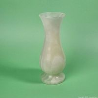 Front view of the polished natural stone bud vase showing its translucent white marbled surface and bulbous form with flared rim.