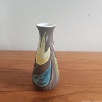 Side view of the 7-inch Jie Gantofta vase showing the brown textured ceramic body with hand-painted abstract leaf motifs in yellow, green, blue, and pink.