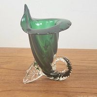 Side angle showing the twisted emerald green glass vase with clear glass spiral base and flared top.