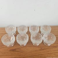 Eight textured pressed glass dessert cups arranged in two rows, showing side and top views of cups revealing details of texture and footed bases