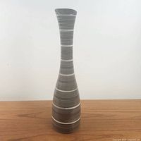Front view of the tall glazed ceramic vase with horizontal grey and white stripes showing its narrow neck and straight upright shape.