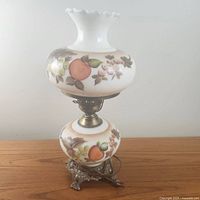 Full view of vintage hurricane lamp showing hand-painted fruit motifs with peaches, grapes, and berries on milk glass globes and ornate metal base