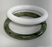 Photo showing white and green jade bangles stacked with white on top, illustrating color and surface finish.