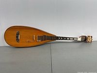 Full view of the 46-inch Asian string musical instrument showing the pear-shaped wooden body, fretboard, and carved headstock with tuning pegs.