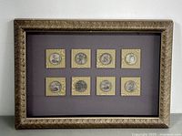 View of all eight silver coins framed and mounted on purple background with gold decorative frame