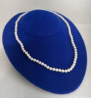 Full view of the freshwater pearl necklace on a blue display bust showing pearl color, size, and necklace length.