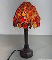 Front and side view of vintage bead table lamp showing amber and red beaded shade and ribbed dark brown base.