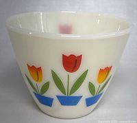 Front view of vintage Fire King milk glass bowl featuring colorful tulip flower design in red, yellow, green and blue.