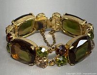 Vintage gold-tone bracelet with large rectangular and round multicolored rhinestones, clasp and safety chain visible. Bracelet shows minor wear typical to vintage jewelry.