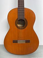 Front view of the Yamaha G-228 classical guitar showing wood grain, sound hole, strings, and bridge.