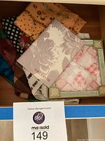 Photo showing a box with eight scarves of various designs and the pamphlet '40 Ways to Tie a Scarf' by Nordstrom.