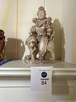 Front view of carved Asian marble statue with figure standing next to lion-like creature and small attendant figure at base.