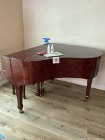 Full view of closed baby grand piano with accessories on top