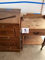 Photo showing both the wooden two drawer file cabinet and the antique wooden bedside table side by side from the front.