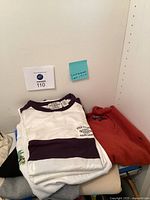 Folded pile of Ralph Lauren shirts including white and black striped Polo T-shirt and red polo sweatshirt