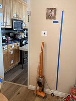 Vacuum cleaner, yardstick, and partial kitchen view showing lot items in their setting