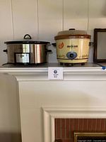 Two crockpots placed on a white mantle: one stainless steel digital Crockpot, one beige Rival Crockpot with retro design and manual dial.