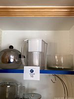 Shelf view showing the silver ice bucket with lid and tongs, the clear water filter pitcher with white top, and the crystal bowl with swan designs.