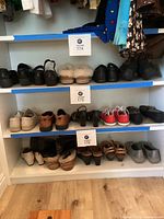 Multiple shelves containing various pairs of women's shoes including red Converse, black heels, casual, and slippers