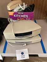 Box with multiple old phones including rotary and cordless models, and associated cords