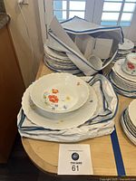 Stack of plates and teacups with floral design, some items in padded carrying case