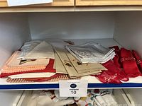 Folded assorted placemats and cloth napkins in various colors and patterns including red napkins with napkin holders