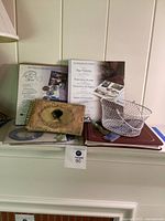 Overview photo showing various scrapbooking supplies including albums, page protectors, patterned cutting tools, and a white basket arranged on a white cabinet.