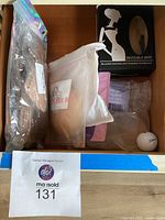 Overview of multiple packages of self adhesive bra cups, a golf ball, and an Invisible Bra box in a drawer.