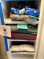 Five men's clothing items folded on a shelf including shorts, sweatpants, and sweaters.