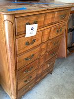 Front view of tall six-drawer wooden dresser with brass handles and carved rounded vertical accents on the corners.