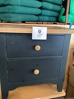 Full front view of the nightstand showing two drawers and green paint with natural wood knobs and base.