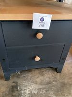 Front view of the nightstand showing two drawers with natural wood knobs and green painted body.