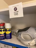 Two cans of WD-40 and the Dustbuster placed on a shelf, showing the front and top views with power cord wrapped.