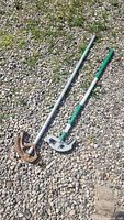 Two pipe benders laying on gravel, showing full length and handles