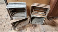 Four wooden crates stacked and arranged on a wood floor showing their condition and size.