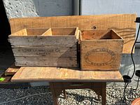 Two wooden advertising boxes side by side on a wooden table.