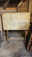 Front view of the antique drafting table showing wooden top and frame
