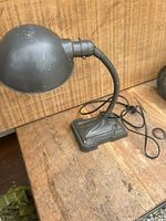 Full view of antique metal desk lamp showing flexible goose neck, bulbous lamp shade, and rectangular base. Lamp surface shows wear and patina.