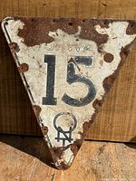 Top-down front view of the triangular Highway 15 Iowa road sign showing rust, screw holes, faded lettering, and theft prevention hole at bottom tip.