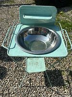 Full front view of antique green metal wash stand with shiny metal basin inset on top, showing overall condition and structure