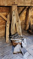 Photo showing multiple large driftwood planks leaning against a wooden wall with additional pieces placed in a container and on the floor.