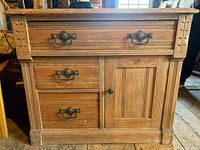 Full front view of Eastlake washstand showing drawers, door, carved details, and wood finish.