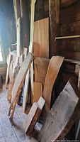 Multiple live edge wood slabs leaning against interior wall, showing varied shapes and sizes