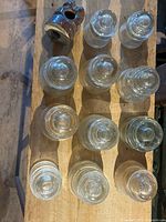 Overhead view of twelve clear glass electrical insulators and one brown ceramic insulator showing tops and bases.