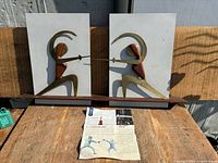Pair of MCM fencing sculptures on white backgrounds with teak base and article in front
