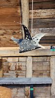 Side view of the metal flying bird sculpture hanging with visible cut-out holes and black and white paint.