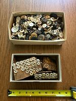 Wide top view of the lot showing two boxes filled with various buttons. The top box has many loose buttons of diverse colors and materials. The bottom box holds several brown display cards with numerous small buttons attached.