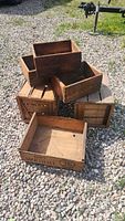 Overview shot of six wooden crates and boxes stacked on gravel ground