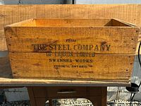 Full view of the wooden box with visible stamped brand and address.